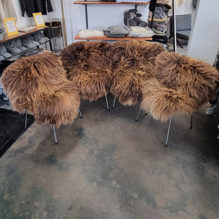 Sæt med brune langhårede lammeskind, fordelt over flere stole i butikken.