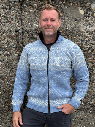 Lyseblå uldcardigan med nordisk mønster over brystet og lynlås, båret af en model.