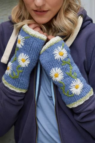 Blå pulsvarmere i uld med hvide margueritter, vist på hænderne.