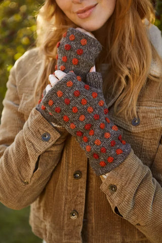 Brune pulsvarmere i uld med røde blomstermotiver, vist på hænderne.