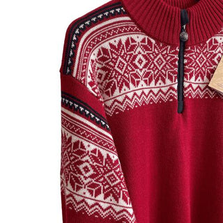Det hvide nordiske mønster og lynlåsen på den røde merinouldsweater, vist tæt på.