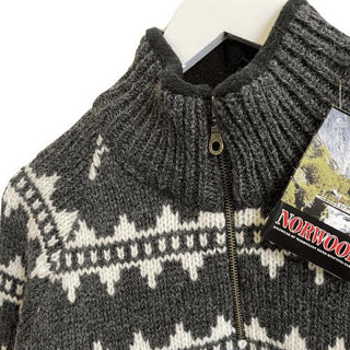 Høj mørk ribkrave og kort lynlås på den islandske uldsweater med hvidt mønster.