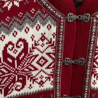 Den røde norske uldcardigans hvide mønster og tinhægter, vist tæt på.
