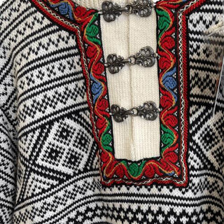 Tinhægter og dekorativt bånd på klassisk norsk sweater, vist tæt på.