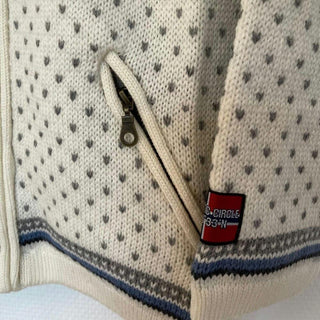 Skrå lynlåslomme, små mørke mønstre og mærke på den hvide windbreaker-cardigan i uld.